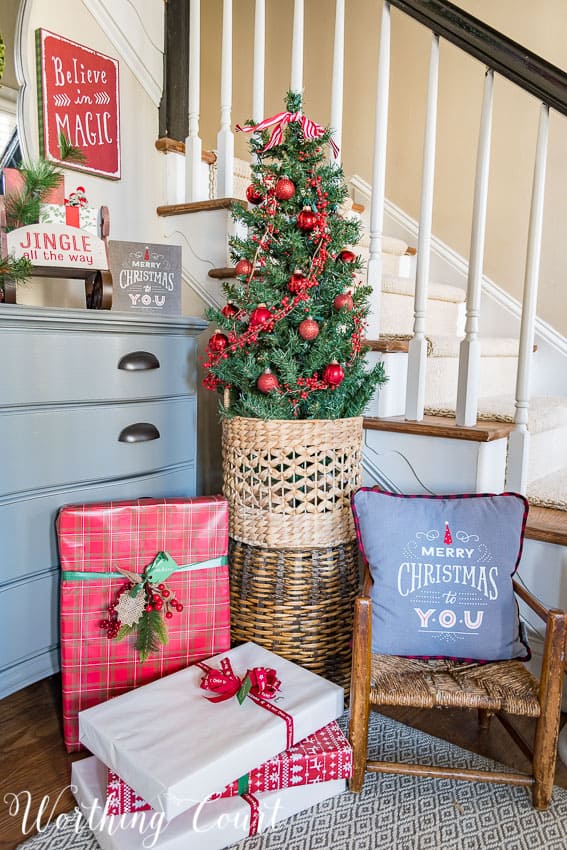 Wrapped Christmas presents in the foyer underneath a small decorated Christmas tree.