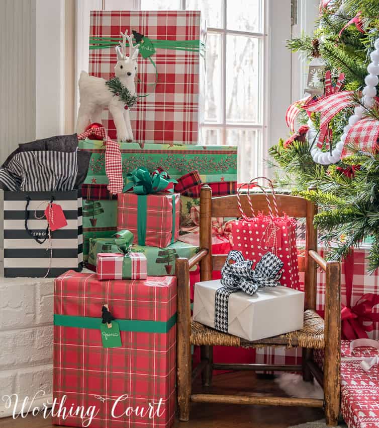 Wrapped Christmas gifts stacked up under and beside the Christmas tree.