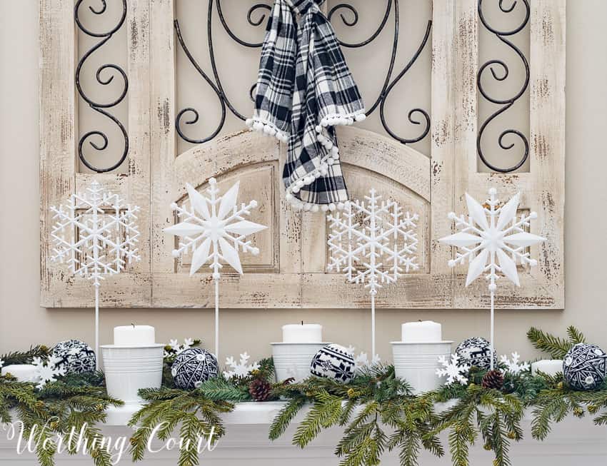 DIY snowflakes on a stick four in a row on the fireplace mantel display.
