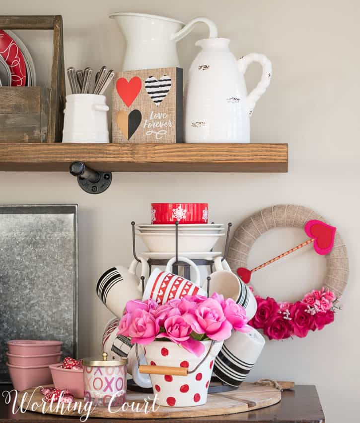 A small Valentine's Day wreath is on the wall beside the open shelves.