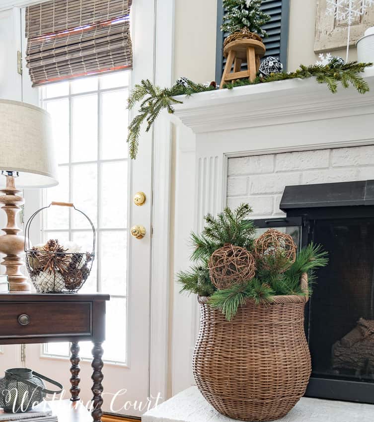 Wicker basket filled with artificial greenery and grapevine orbs for winter.