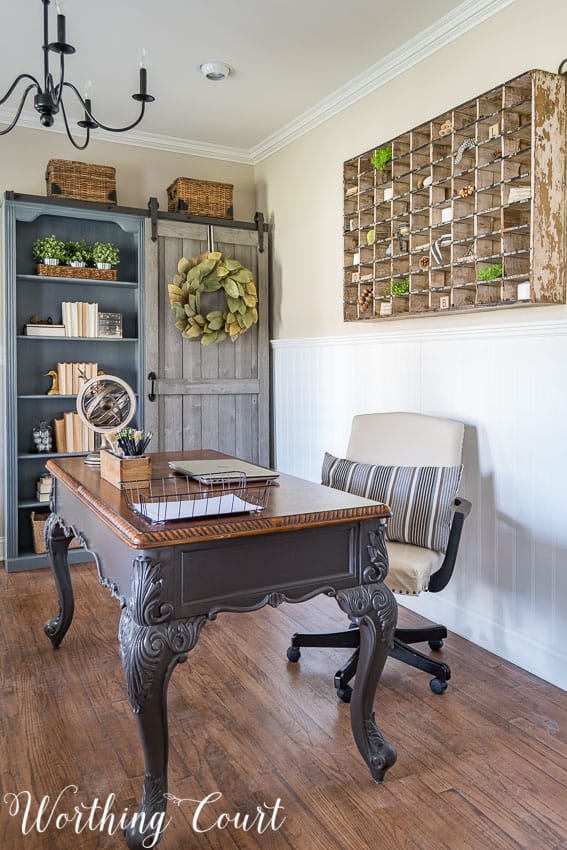 home office with bookcase, desk and antique mail sorter on the wall