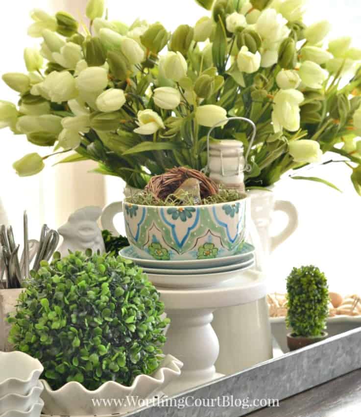 Spring centerpiece with white tulips and greenery around it.