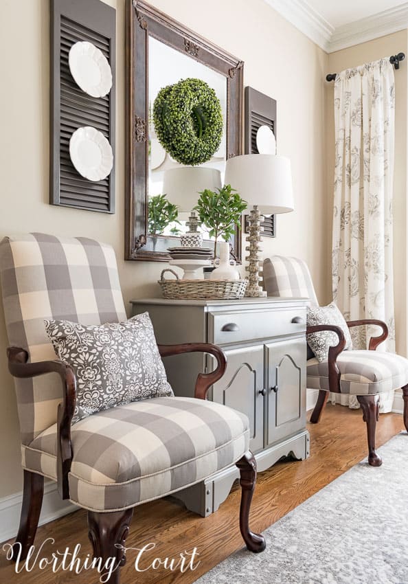 Two armchairs with throw pillows and in-between is a small console table.