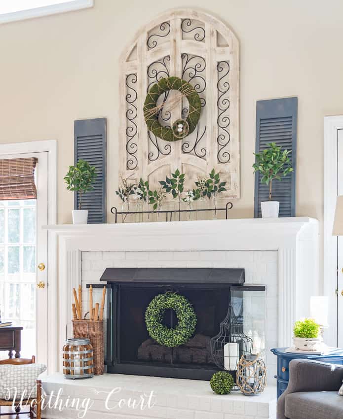 A fresh and easy farmhouse style spring fireplace with neutral tones and the moss covered wreath on the fireplace and the mantel.