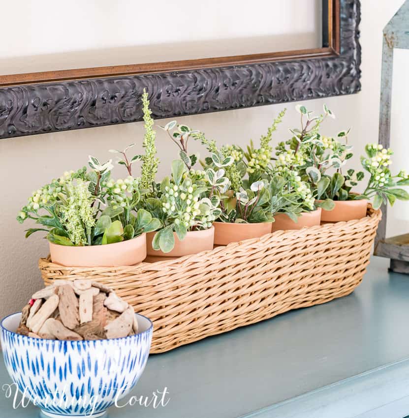 Clay pots inside a narrow basket on the top of the drawers.