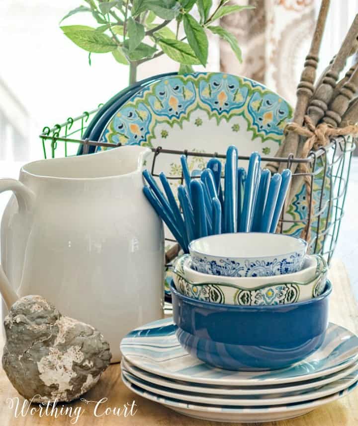 Centerpiece with blue white and green dishes on a breadboard.