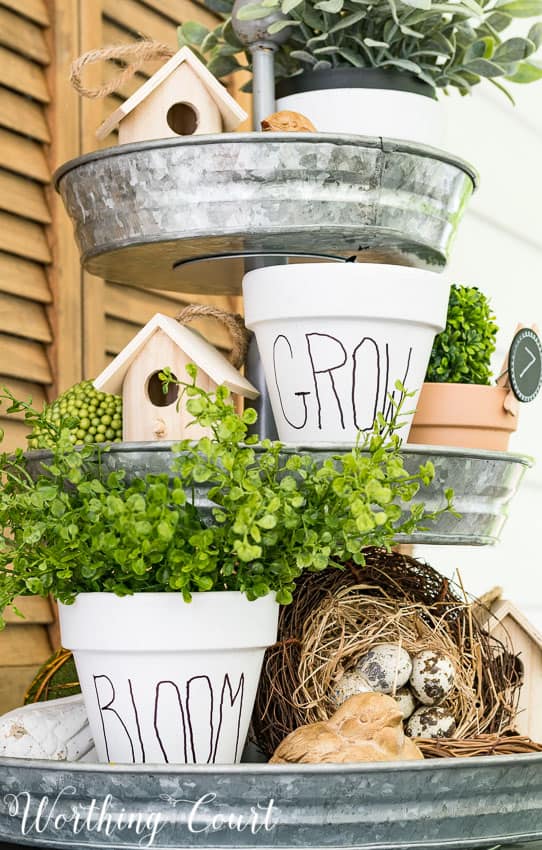 The white pots with black words on them such as grow and bloom on a tiered tray.