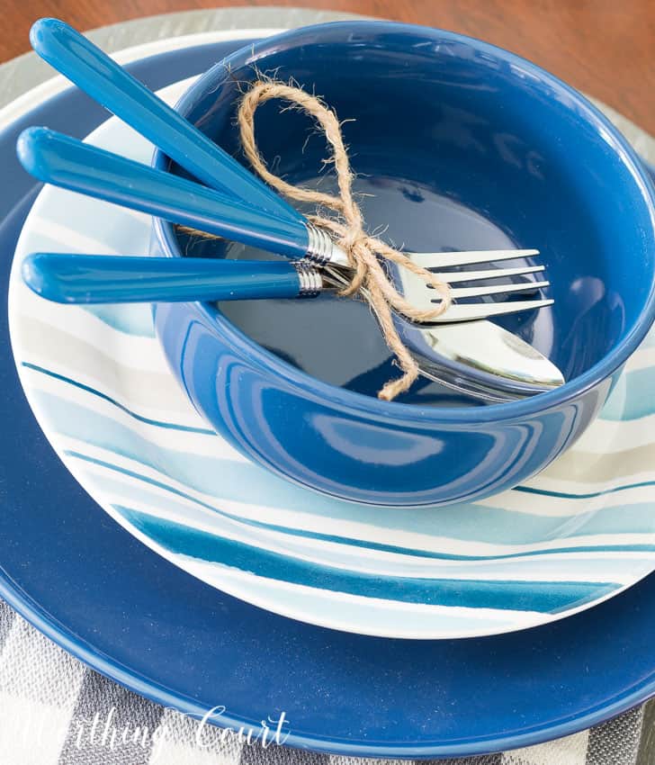 Summer place setting with blue and white dishes and cutlery.