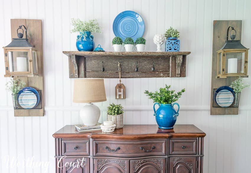 Summer sideboard decor with a lamp, blue vase and a vintage wooden shelf.