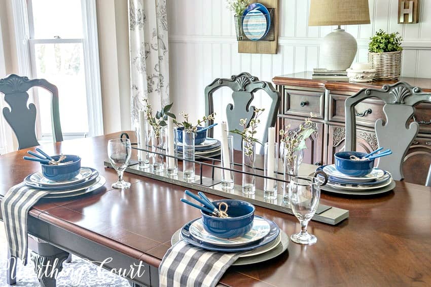 Summer tablescape with blue, white and gray with clear glass and greenery centerpiece.