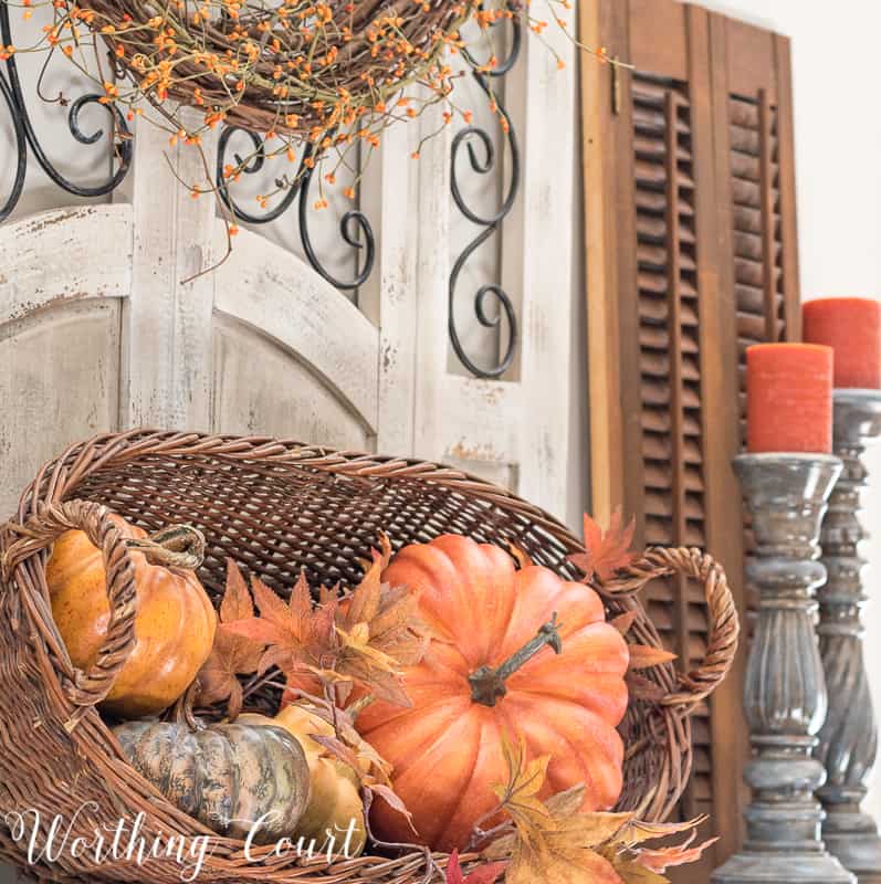 wicker basket filled with orange pumpkins on fireplace mantel