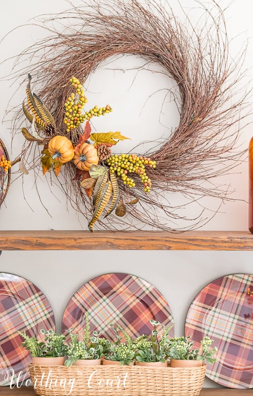 Make a super easy fall wreath by tucking a couple of faux floral bushes in between the stems of the wreath. Done in 5 minutes! This wreath is on the wall by the shelves.