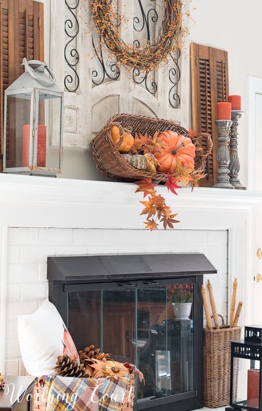 A rustic basket filled with faux pumpkins and faux fall leaves || Worthing Court #falldecor #rustic #mantel