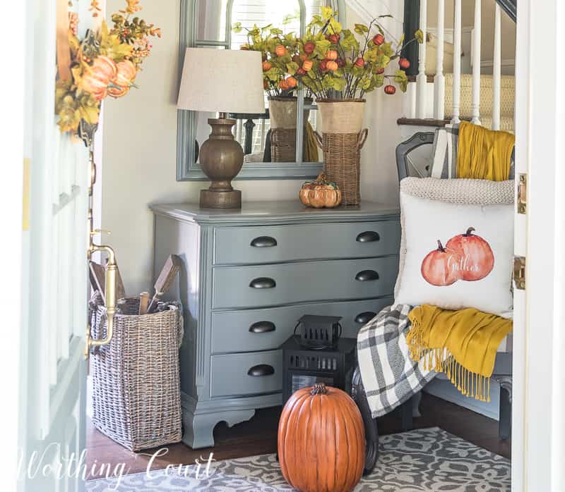 Foyer decorated for fall with a pumpkin on the floor, and fall leaf decor.