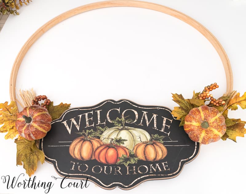 Attaching the small pumpkins and leaves beside the welcome to our home on the hoop.