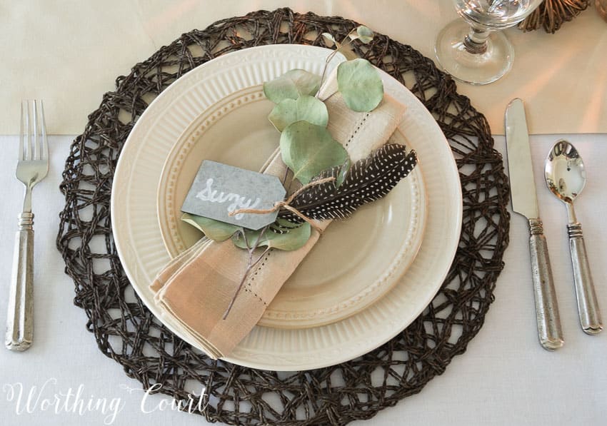 place setting with brown placemat, white dishes and neutral linen napkin