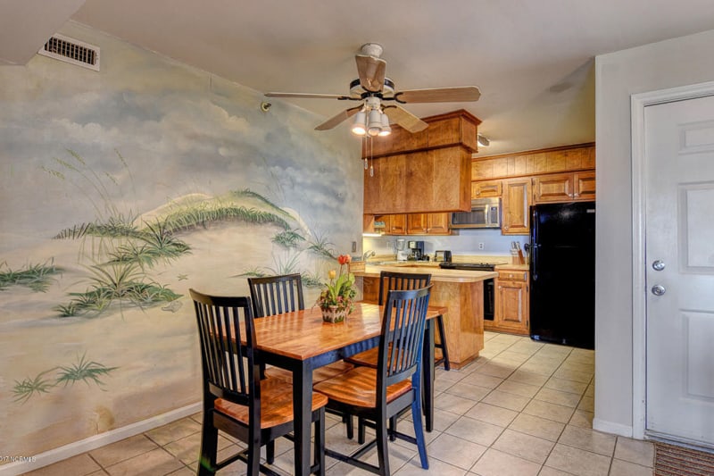 Dining Room with a small wooden table, a mural on the wall and an old fan/light above the table.