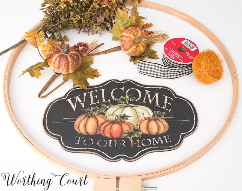 The embroidery hoop, small pumpkins, ribbon, and a sign saying welcome to our home all out on the counter.