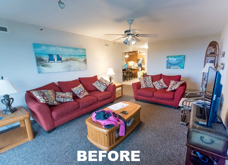A before picture of a dated living room with pink couches, old coffee table and ceiling fan.