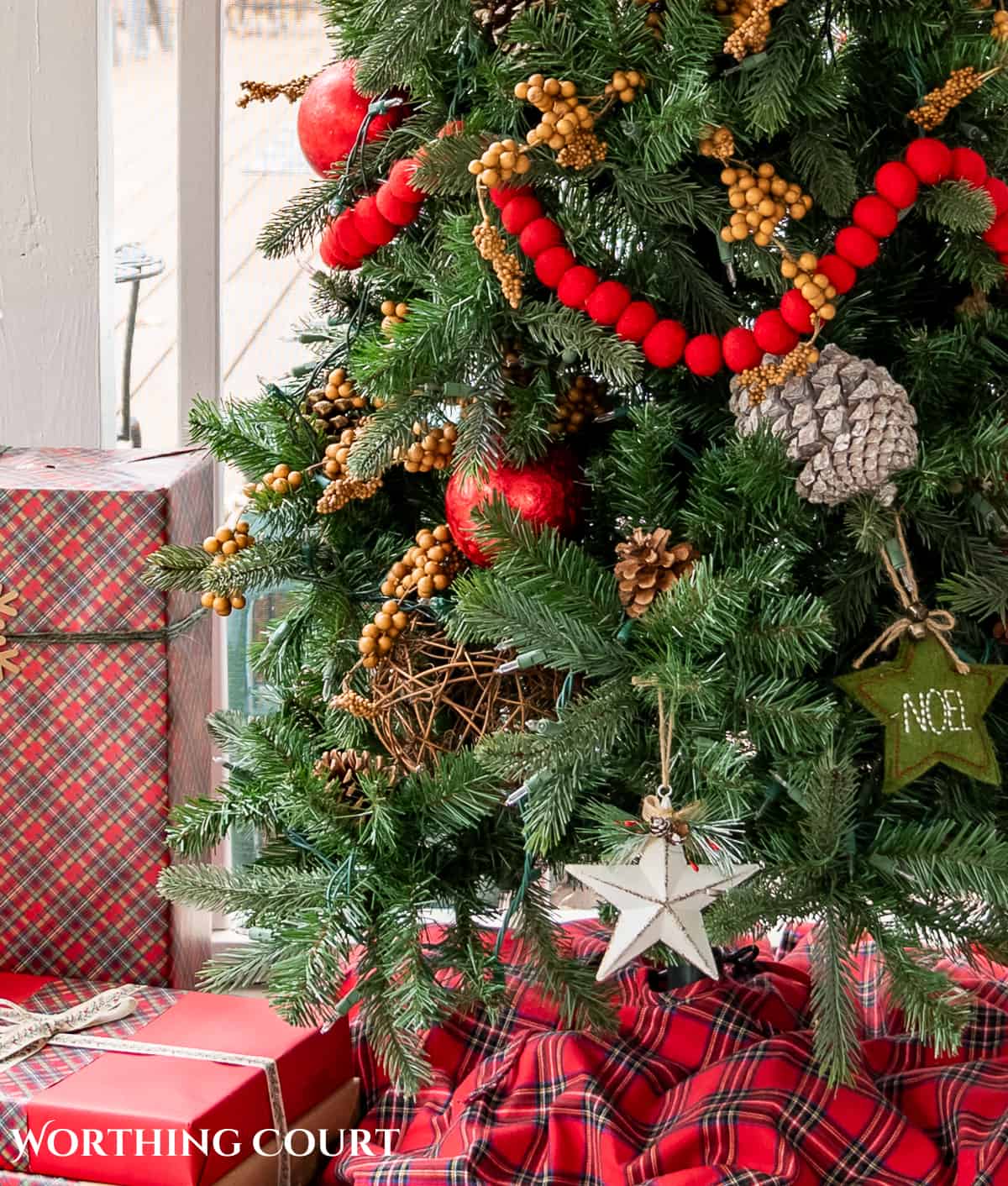 bottom corner of skinny Christmas tree on a screen porch decorated with outdoor type ornaments