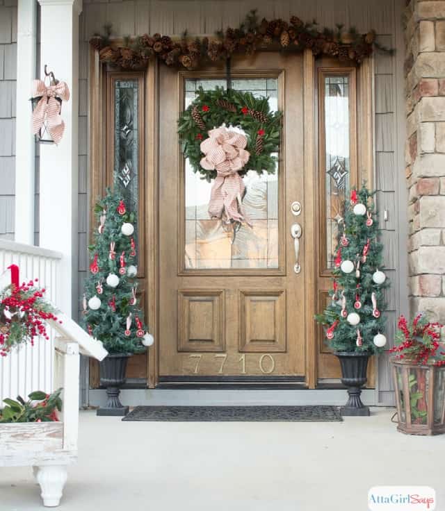 A wooden front door with window in it, plus a Christmas wreath hanging on the door.