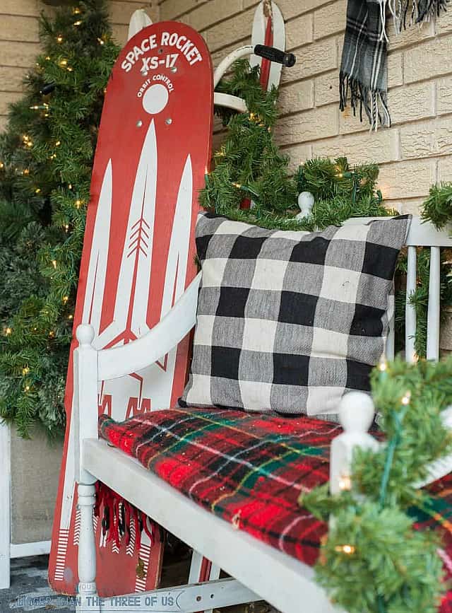 A small bench with a buffalo checked pillow is on the porch.