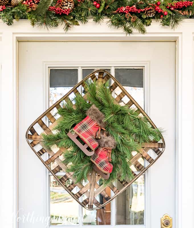 Tobacco basket Christmas wreath is hanging on the front door of the house.
