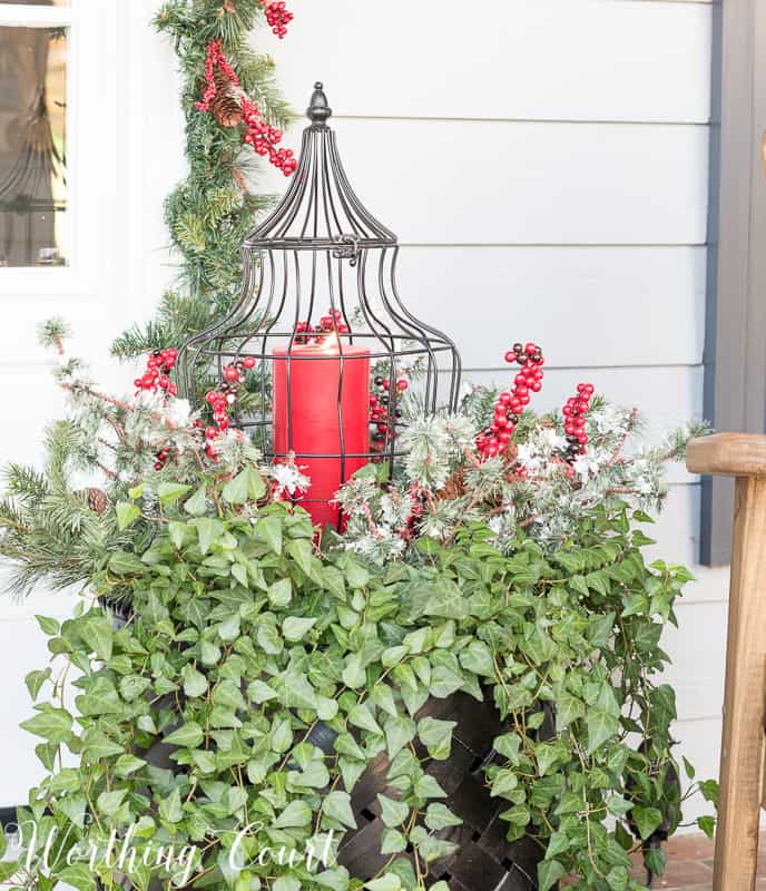 Christmas outdoor container filled with ivy, faux greenery and a lantern #christmas #christmascontainer #christmasurn