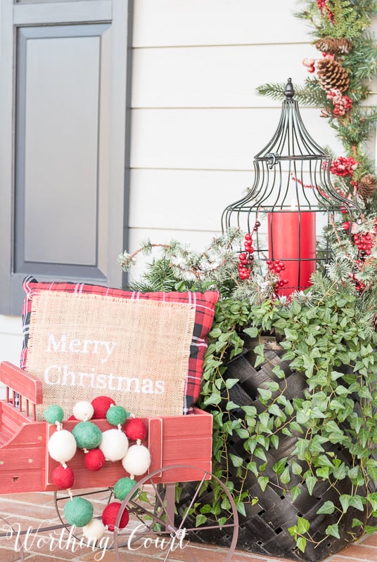 A red, white and green garland is in the rustic Chrismtas carriage.