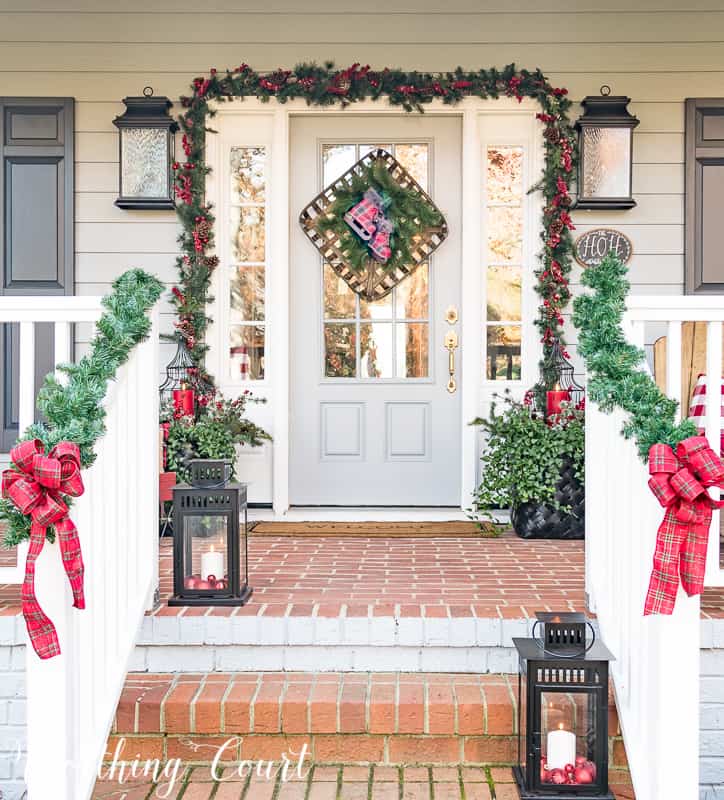 There are large black lanterns with candles in them lining the stairs to the front porch.