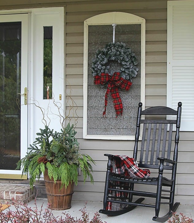 A black rocking chair with a plaid blanket is on the front porch.