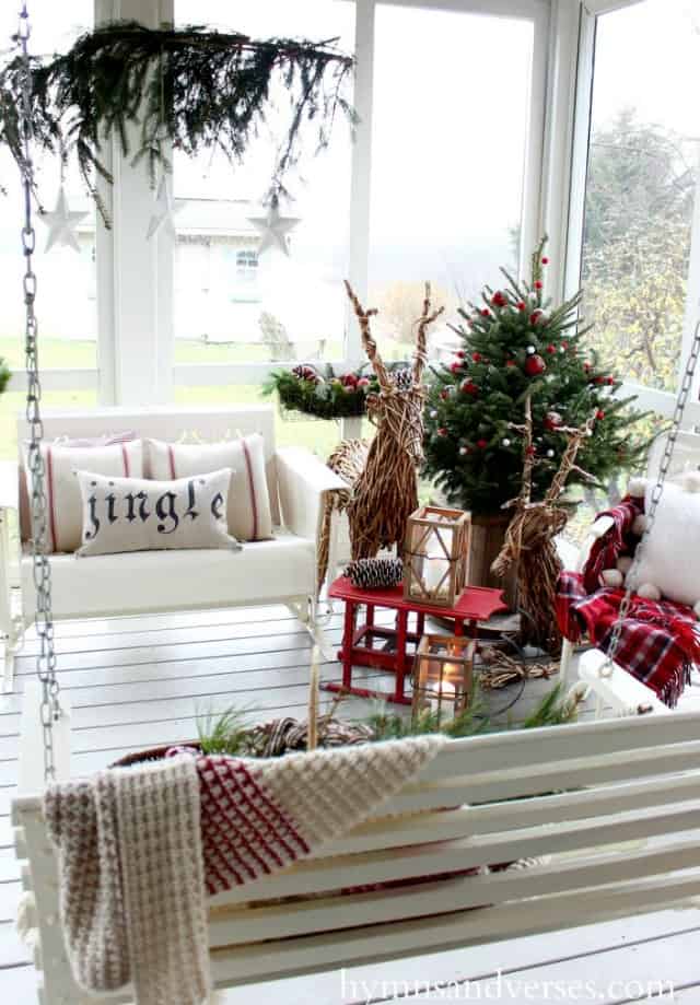 Twig deers, a small swing bench and a small Christmas tree is on the white porch.