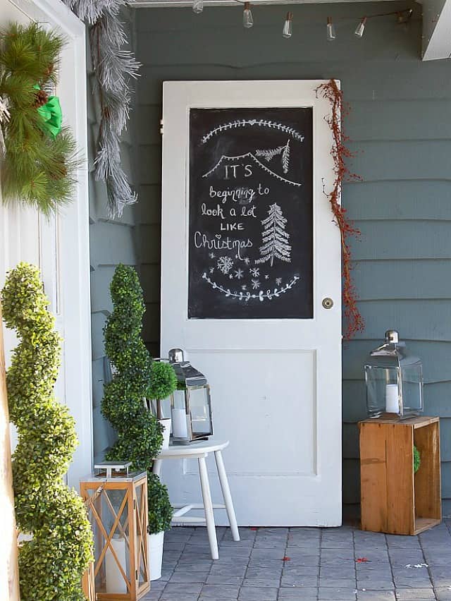 There is a white door with chalkboard beside the front door on the porch.