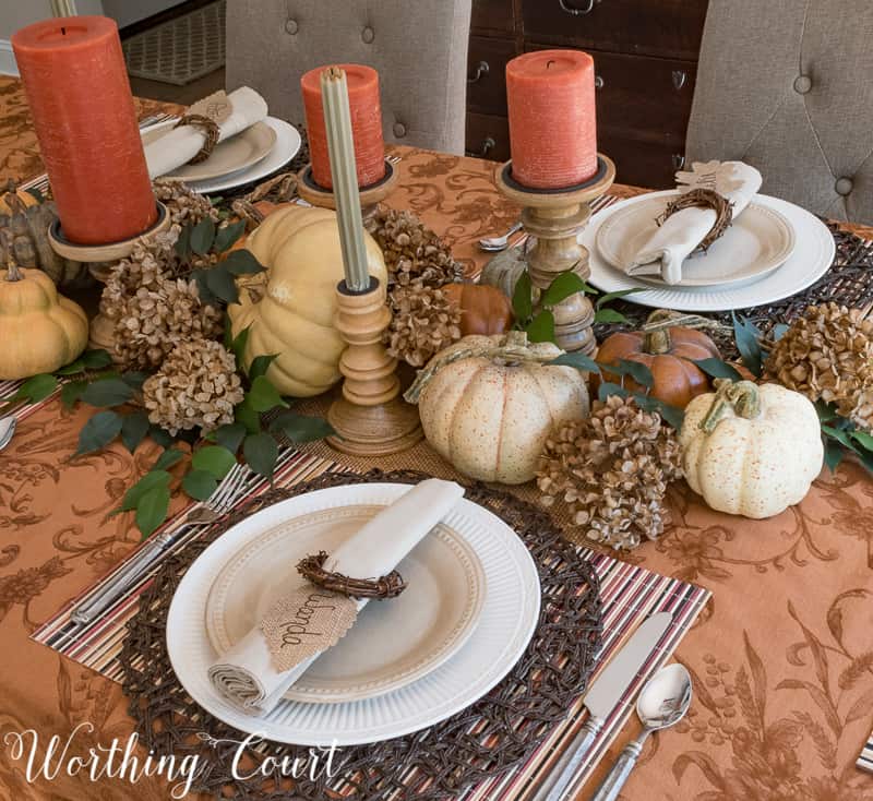 The place setting has a charger and there are orange candles.