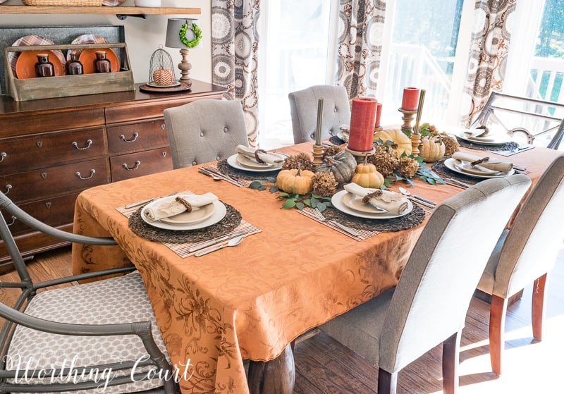 The dining room table with a gold tablecloth and a pumpkin centerpiece.