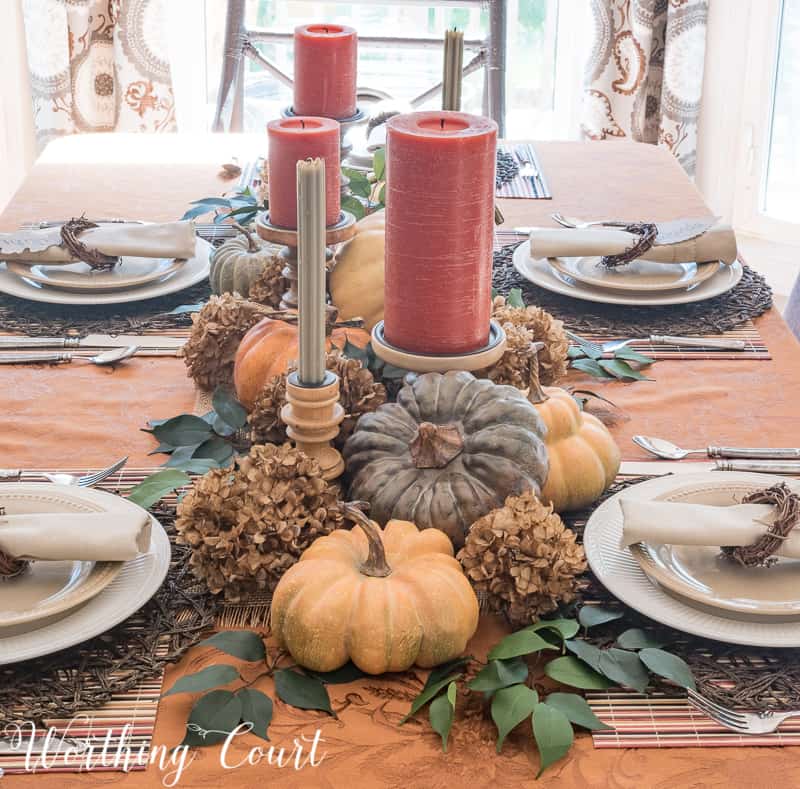 A small thoughtfully place mini pumpkins and candles make up the centerpiece.
