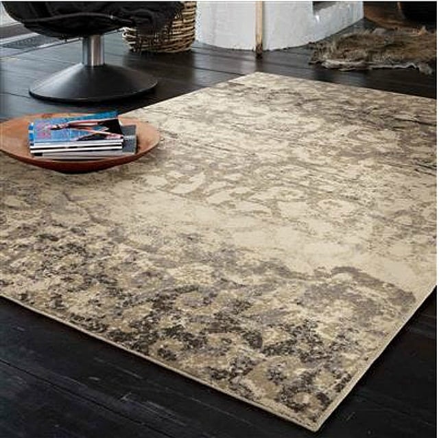 Buxton Bliss Lambswool Area Rug that is neutral in tone on a wooden dark floor.