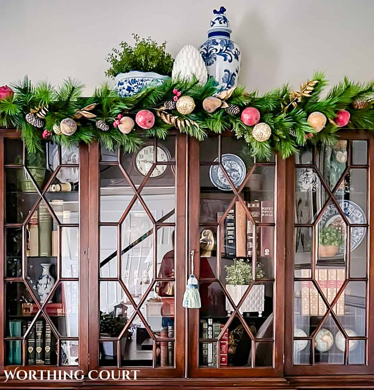 wood china cabinet with glass doors with a Christmas garland across the top