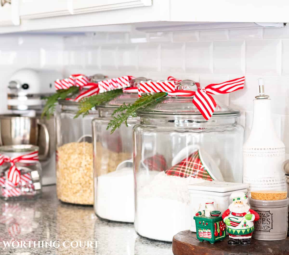 clear glass canisters with red and white striped ribbon and faux Christmas greenery tied to the top