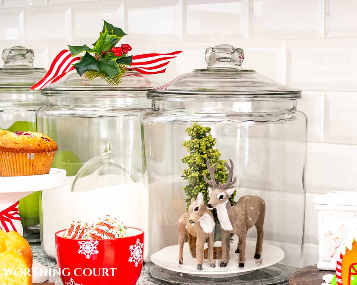 clear glass cannister filled with deer Christmas ornaments and a bottle brush tree for Christmas