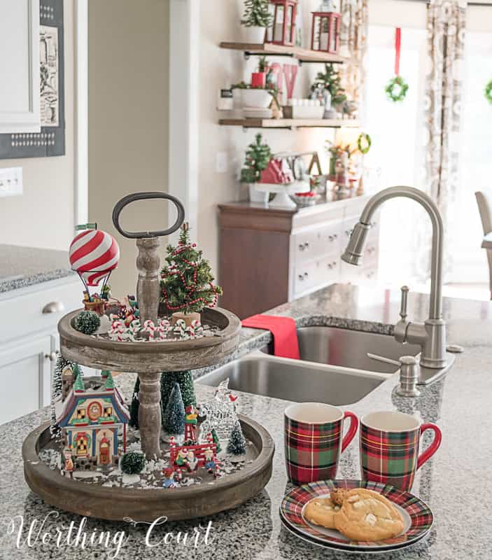 There are two coffee cups on the counter and a plate filled with cookies.