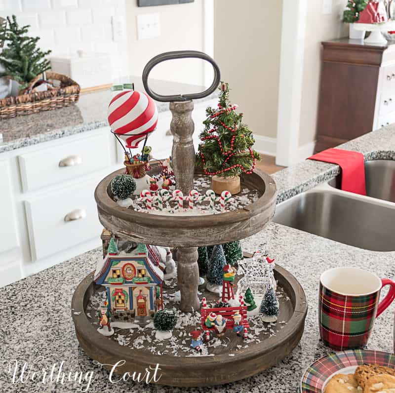 A wooden tray has holiday decorations plus candy canes on it.