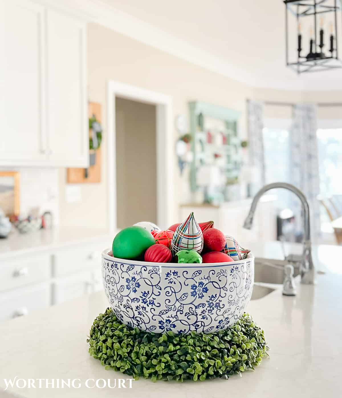 large blue and white bowl filled with red, green and blue Christmas ornaments on a kitchen island