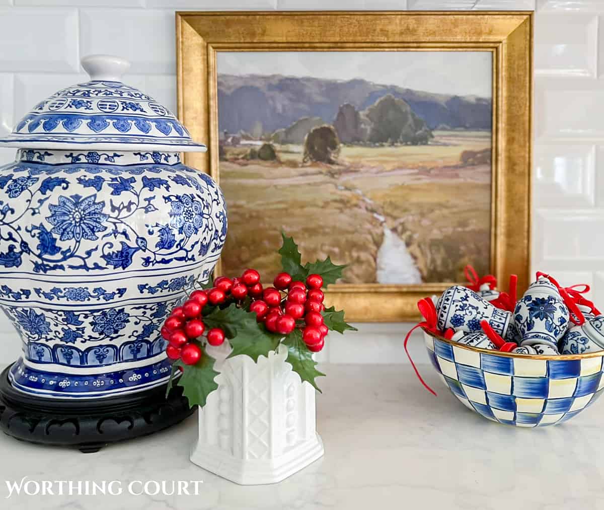 Christmas vignette on a kitchen counter with blue and white accessories and red berries in a small vase