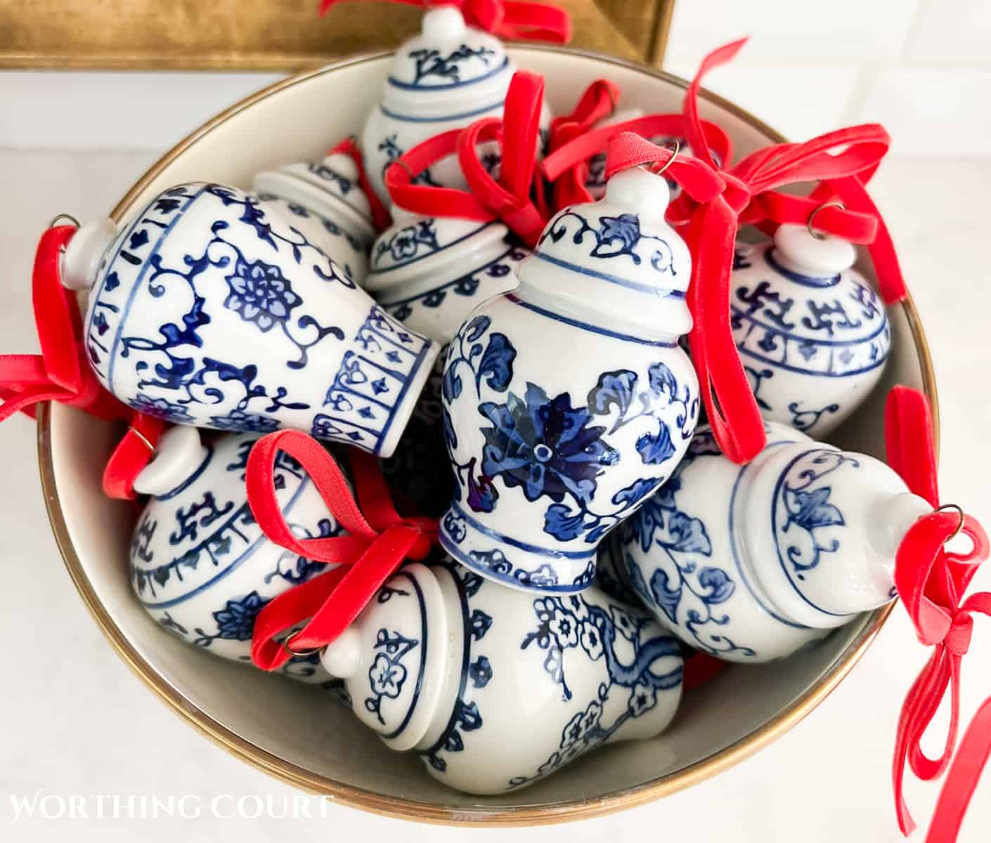 bowl filled with minature blue and white ginger jar Christmas ornaments with red velvet ribbon bows