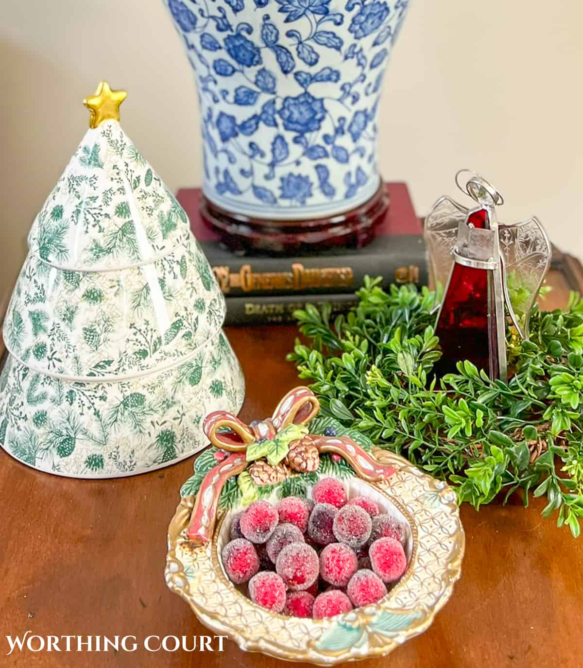 Angel, ceramic Christmas tree and bowl of red berries on a wood end table for Christmas