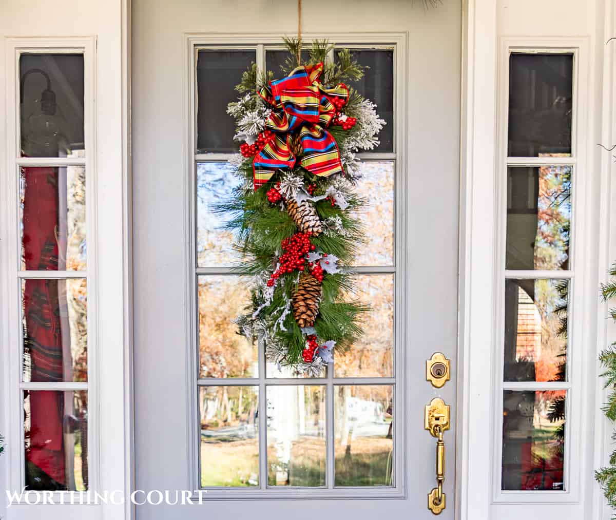 Christmas swag hanging on a gray front door with glass panes