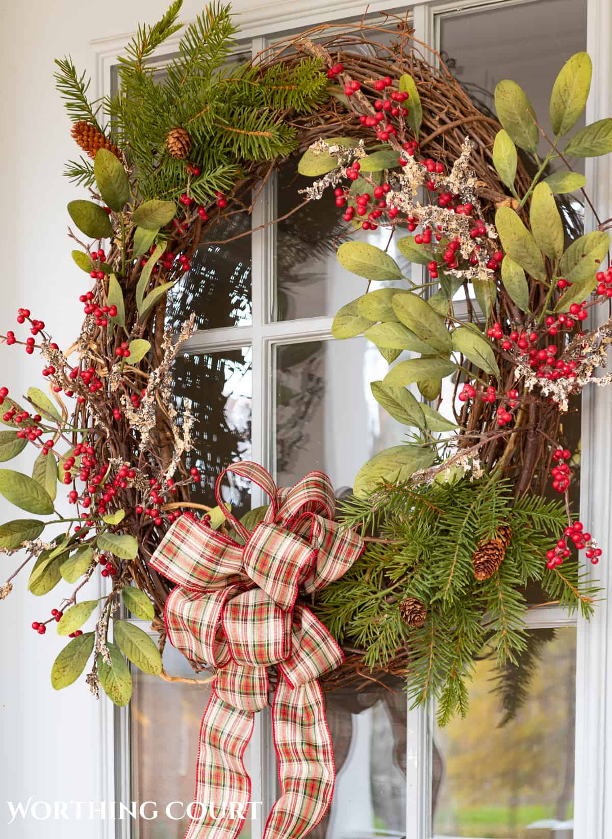 Christmas wreath with natural elements hanging on a front door with glass panes