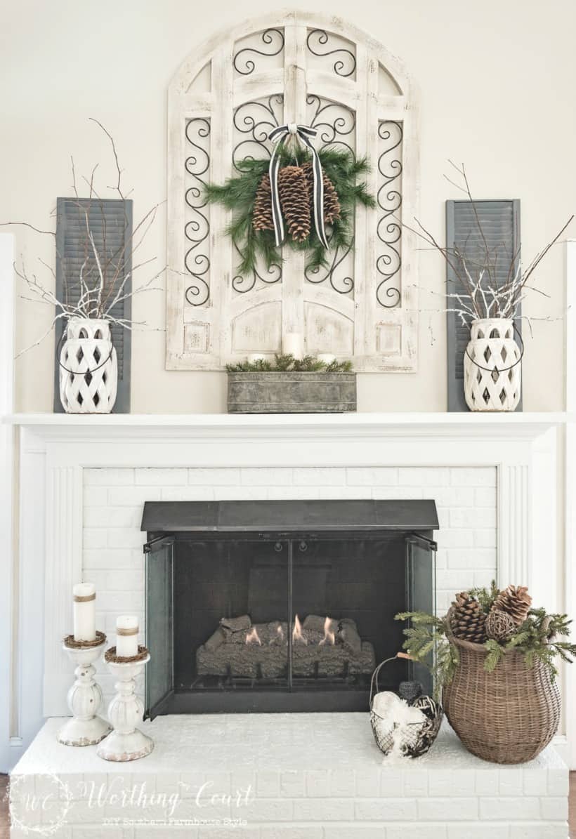 Fireplace decorated for winter with a wicker basket in front of the fireplace.